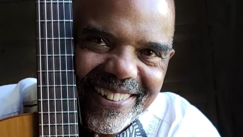 man hugging a guitar while smiling