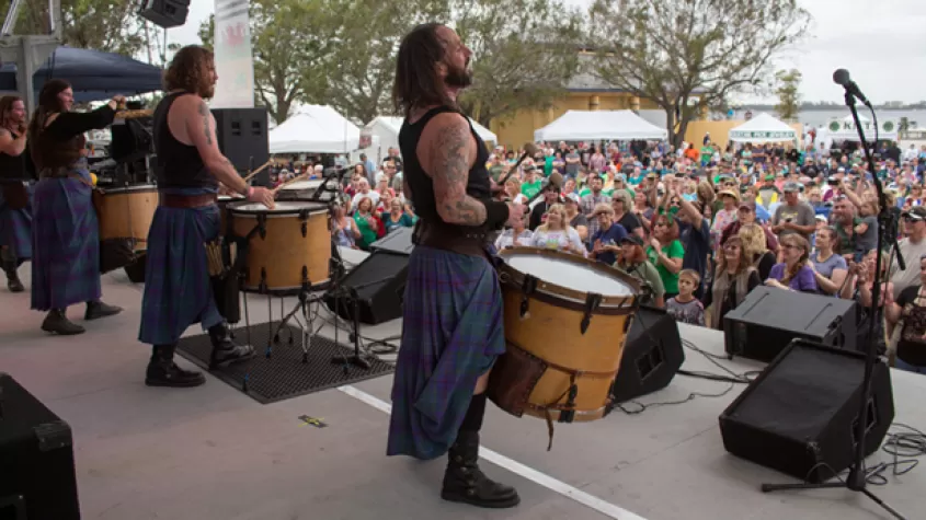Performers on stage looking out at audience in chairs on lawn