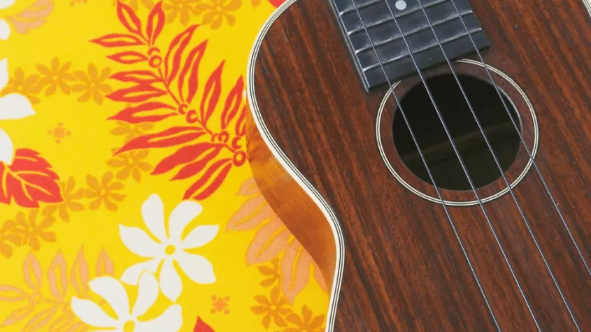 Yellow background with white, red and pink florals and a brown ukulele 