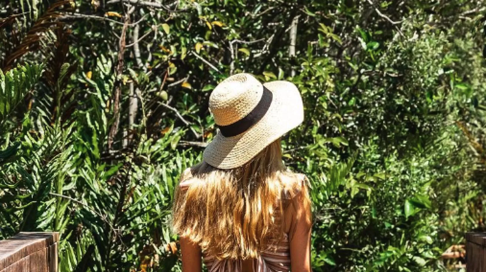A woman walks down a boardwalk in a nature preserve