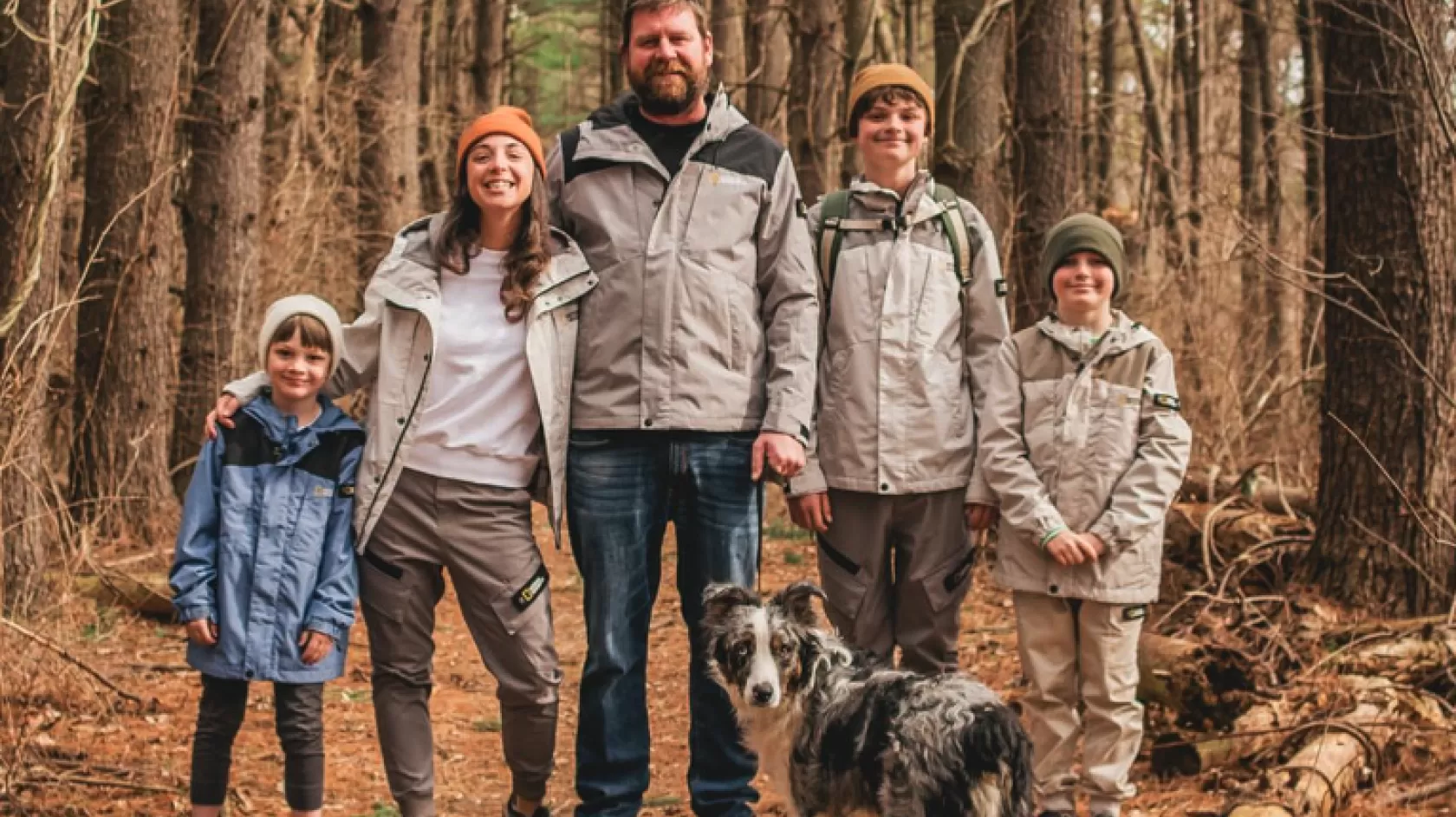 A family poses outside in the woods