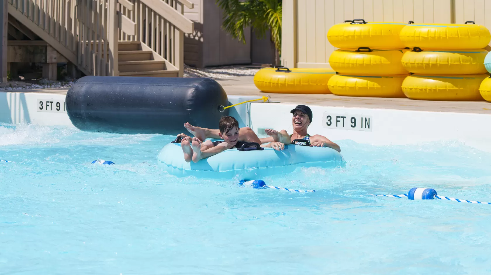 A mother and child float in the pool on a tube after completing a water slide