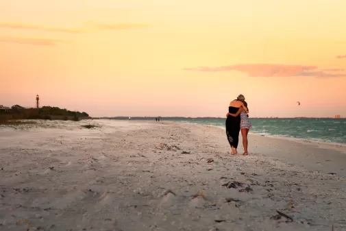 Two people hugging on a beach at sunset 