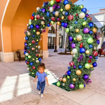 A young girl walks through a holiday wreath at a shopping center